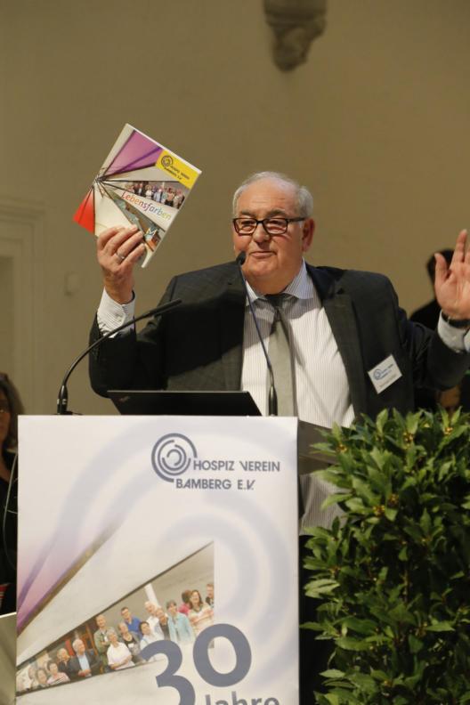 Konrad Göller hält die Festschrift 'Lebensfarben - 30 Jahre Hospizverein Bamberg' in Händen